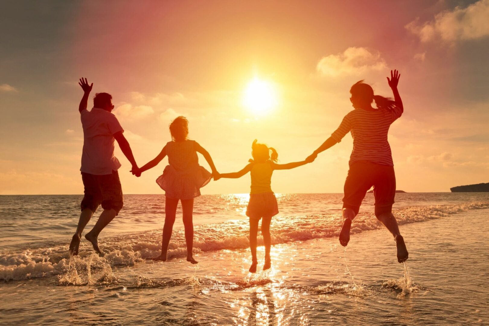 A group of people jumping in the air at sunset.