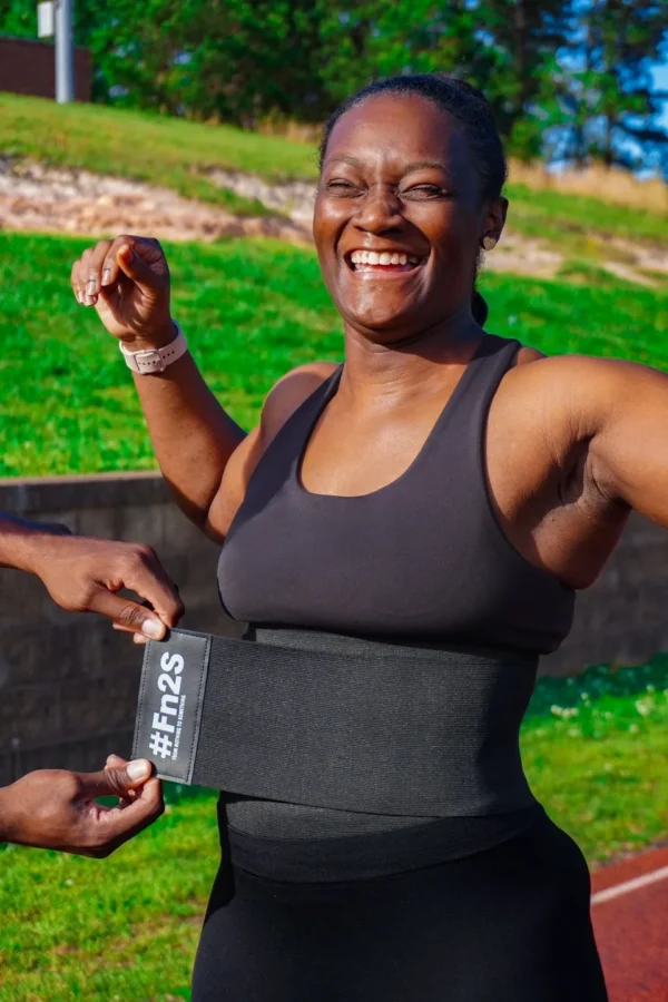 A woman wearing a black belt and smiling.