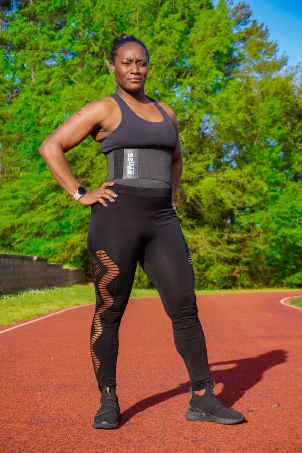 A woman standing on top of a track wearing black pants.