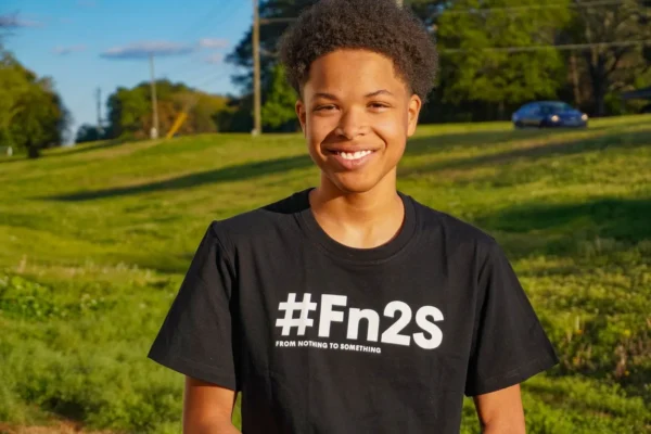 A young person wearing a black shirt in the grass.