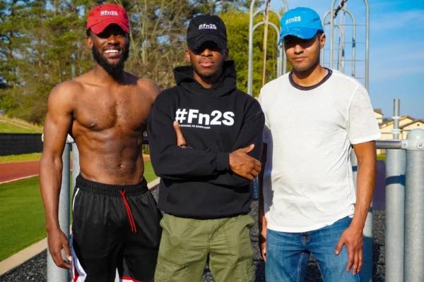 Three men in hats and shorts posing for a picture.