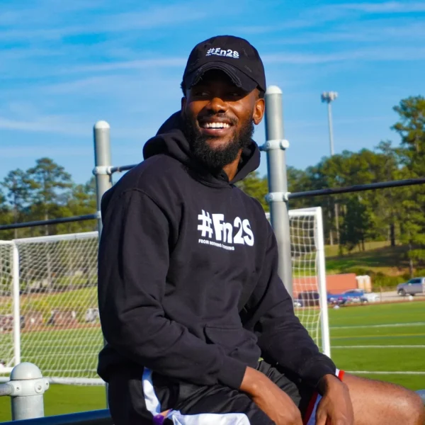 A man sitting on top of a bench in front of a soccer goal.