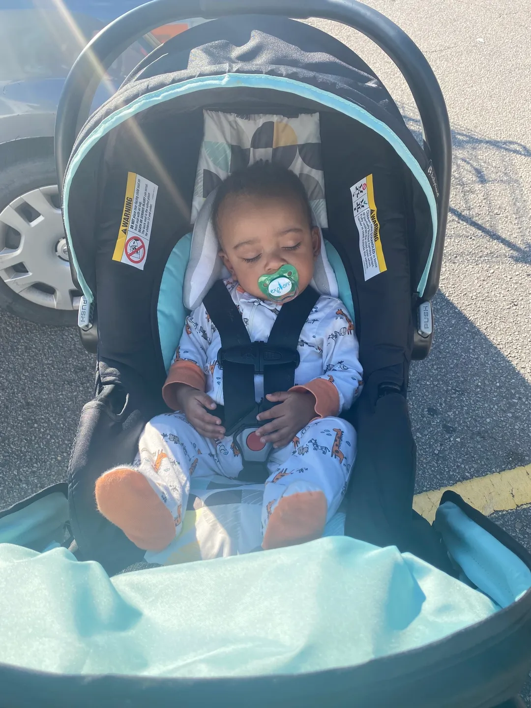 A baby in a stroller with its head down.